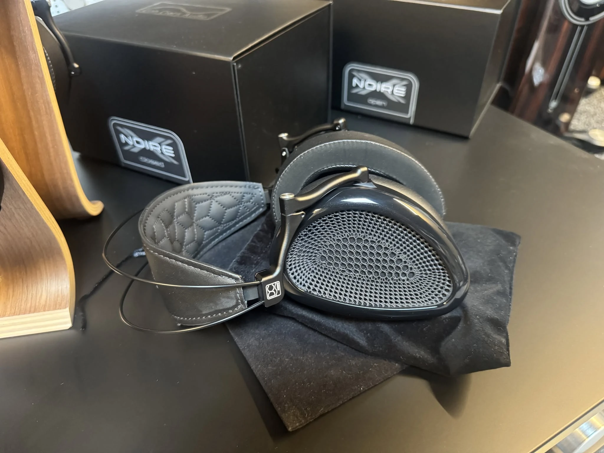 Dan Clark Audio NOIRE XO open-back headphones on a table with NOIRE product boxes in the background