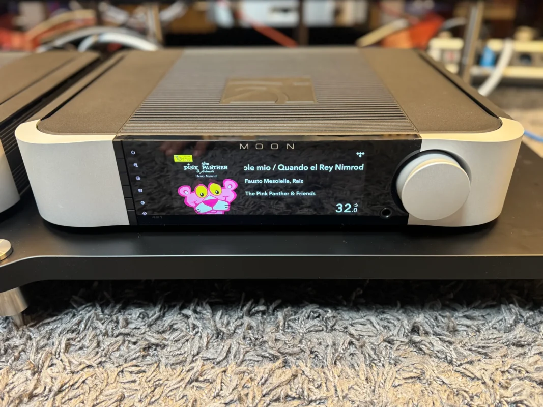 MOON Compass 491 network player and preamplifier with album artwork on its display and a silver volume control.